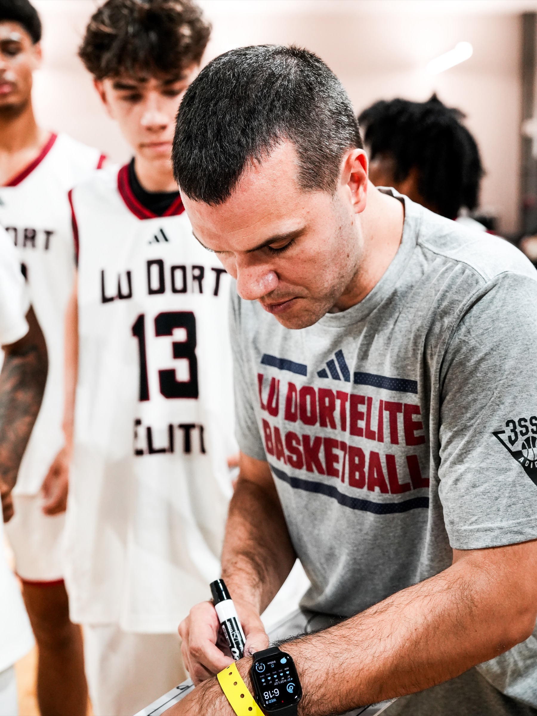 Joey McKitterick writing on a clipboard during basketball practice.