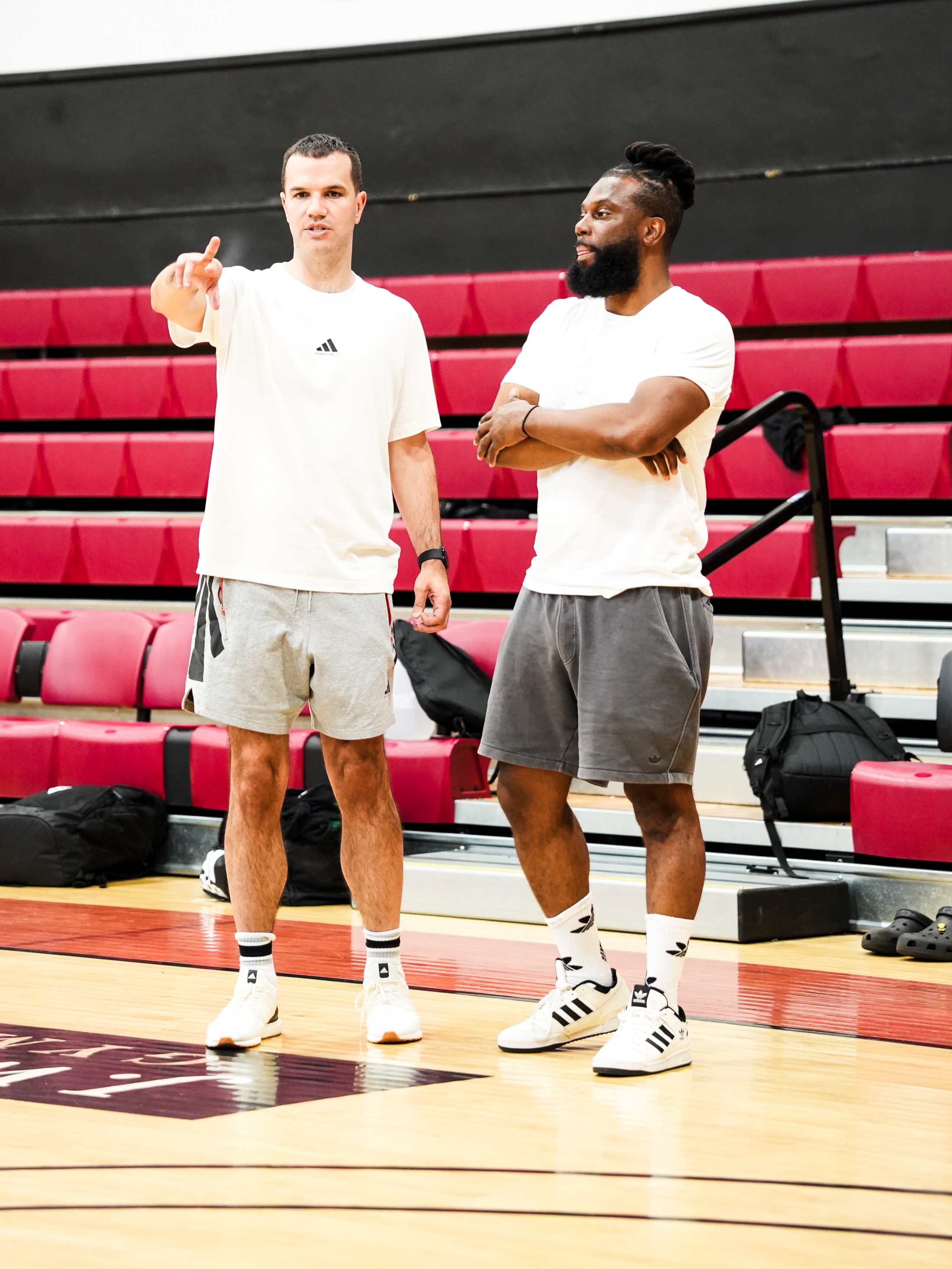 Joey McKitterick points across a basketball court while Nelson Ossé stands beside him during practice.